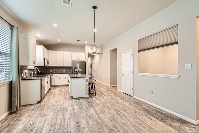 kitchen featuring visible vents, dark countertops, a breakfast bar, a sink, and appliances with stainless steel finishes