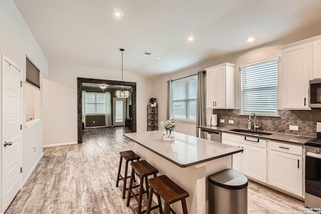 kitchen featuring decorative backsplash, visible vents, appliances with stainless steel finishes, dark countertops, and a sink