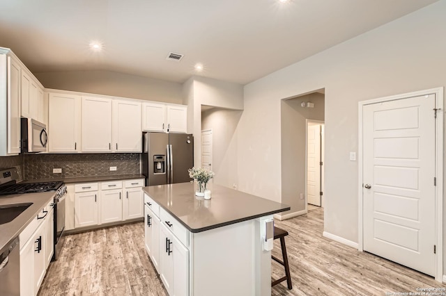kitchen featuring appliances with stainless steel finishes, tasteful backsplash, light wood-style flooring, and visible vents