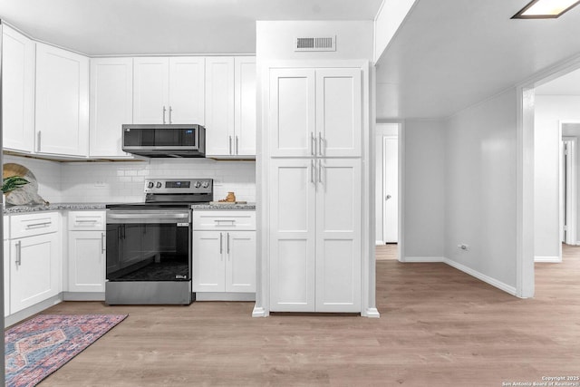 kitchen with decorative backsplash, visible vents, appliances with stainless steel finishes, baseboards, and light wood-style flooring