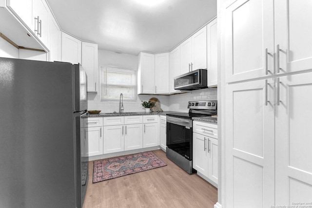 kitchen with white cabinets, stainless steel appliances, a sink, and light wood-type flooring
