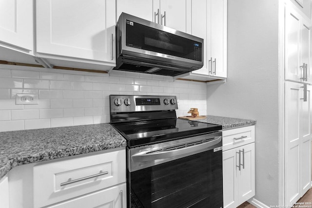 kitchen with tasteful backsplash, light stone countertops, stainless steel appliances, and white cabinetry