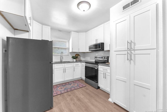 kitchen with visible vents, light wood-type flooring, a sink, stainless steel appliances, and white cabinetry