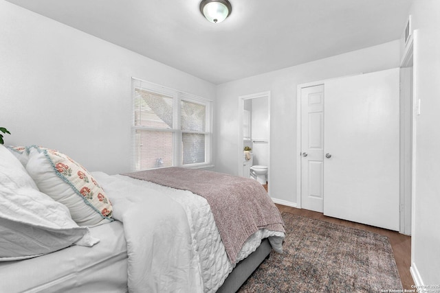 bedroom featuring baseboards, ensuite bathroom, wood finished floors, and visible vents