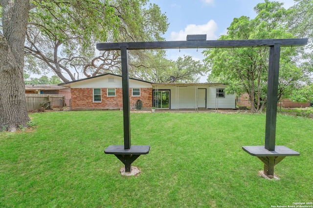 back of property with a lawn, fence, and brick siding