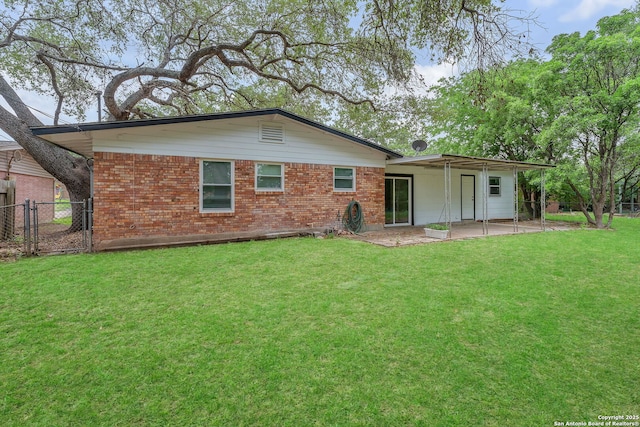 back of house featuring fence, brick siding, a gate, a patio area, and a lawn