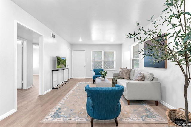 living room featuring visible vents, baseboards, and wood finished floors