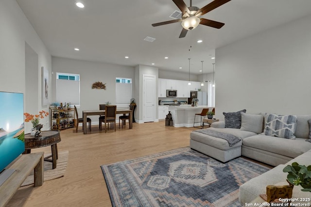 living room featuring a ceiling fan, visible vents, recessed lighting, and light wood-type flooring
