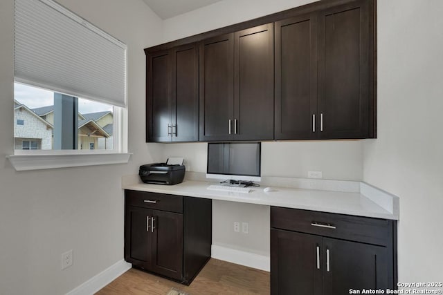 unfurnished office featuring baseboards and light wood-type flooring