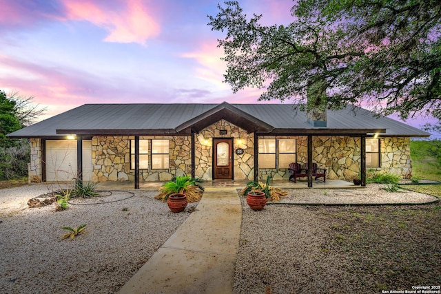 view of front of home with a porch, metal roof, and stone siding