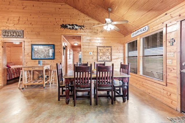 dining area with wood walls, concrete flooring, lofted ceiling, and ceiling fan