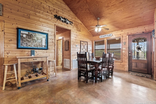 dining area with wood walls, a wealth of natural light, lofted ceiling, and finished concrete flooring
