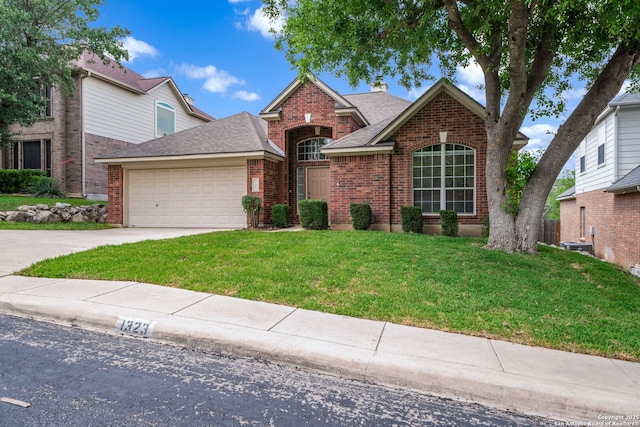 traditional-style house featuring a garage, a front yard, a chimney, brick siding, and driveway