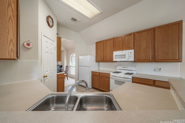kitchen with a sink, decorative backsplash, white appliances, and lofted ceiling