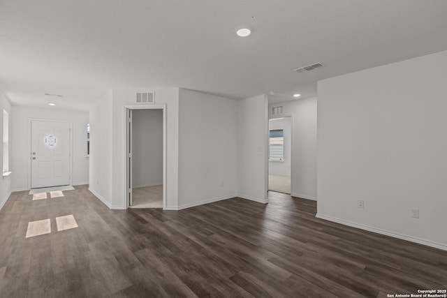 unfurnished living room featuring baseboards, dark wood finished floors, and visible vents