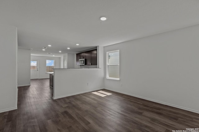 unfurnished living room with baseboards, recessed lighting, and dark wood-type flooring