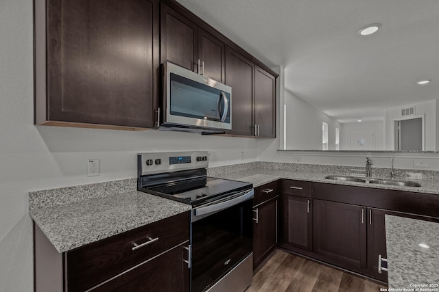 kitchen with dark brown cabinetry, visible vents, a sink, dark wood-style floors, and stainless steel appliances