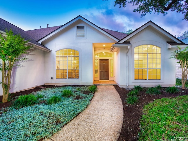 view of front of house with a shingled roof and stucco siding