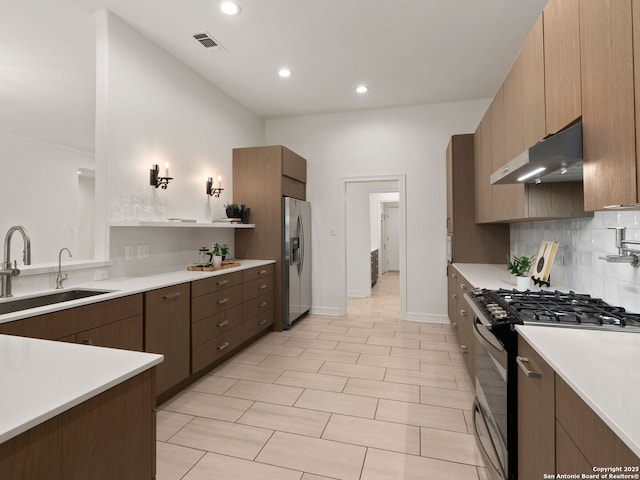 kitchen with visible vents, gas range, a sink, stainless steel fridge with ice dispenser, and under cabinet range hood