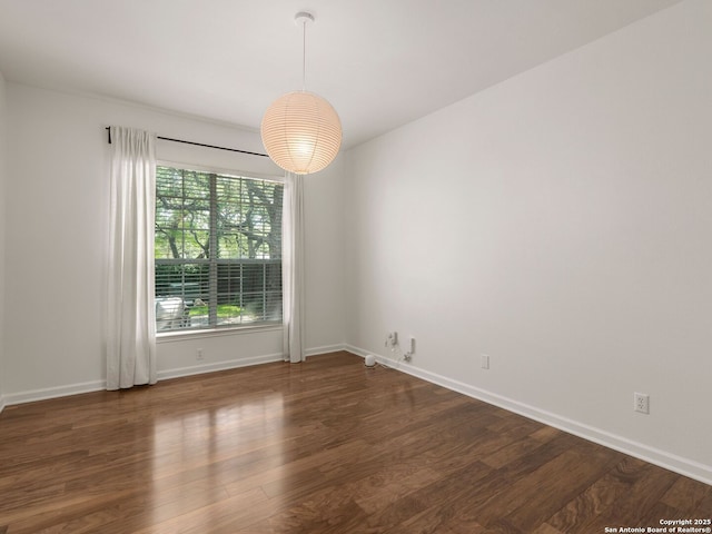 unfurnished room featuring dark wood-type flooring and baseboards