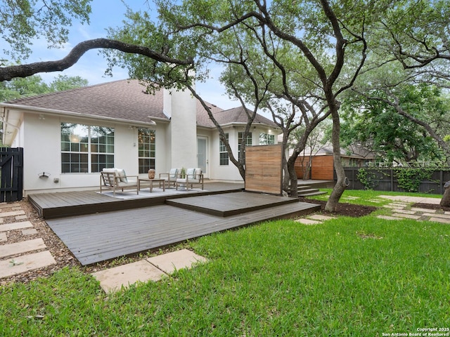 back of house with a lawn, a shingled roof, stucco siding, and fence