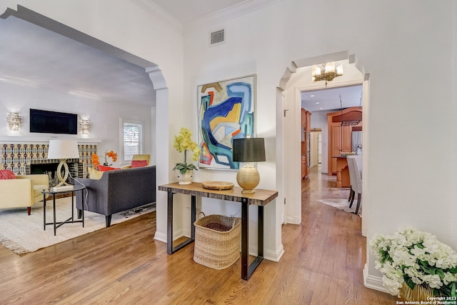 402 Thelma Dr, Olmos Park, TX 78212 - entrance foyer featuring crown molding, an inviting chandelier, arched walkways, wood finished floors, and visible vents
