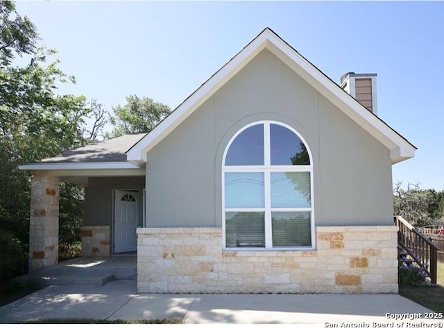 exterior space featuring a carport, stone siding, and stucco siding