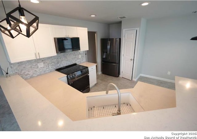 kitchen featuring backsplash, light countertops, white cabinets, black appliances, and recessed lighting