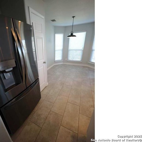 kitchen with hanging light fixtures, stainless steel fridge, baseboards, light tile patterned floors, and visible vents