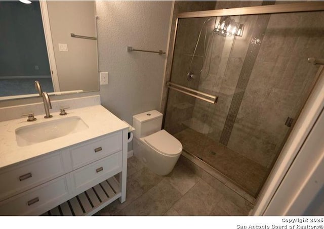 bathroom with toilet, tile patterned floors, a shower stall, and vanity