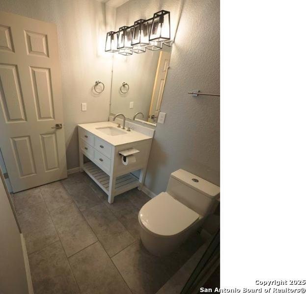 bathroom with vanity, tile patterned flooring, baseboards, and toilet