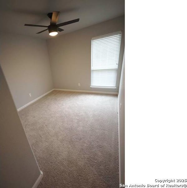 carpeted empty room featuring baseboards and ceiling fan