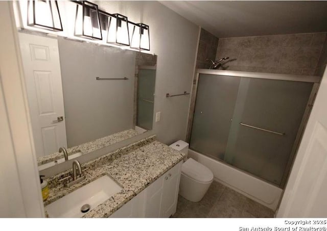 full bathroom featuring vanity, tile patterned floors, combined bath / shower with glass door, and toilet