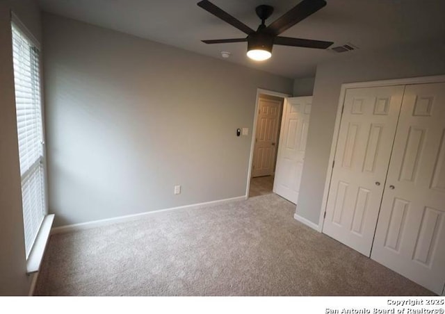 unfurnished bedroom with carpet flooring, ceiling fan, baseboards, visible vents, and a closet