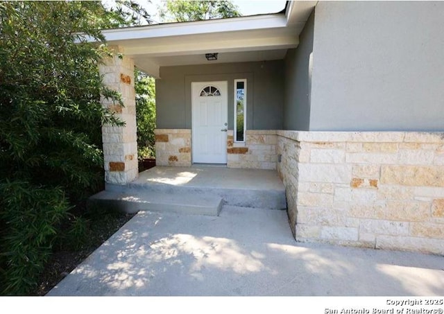 property entrance featuring stucco siding, a porch, and stone siding