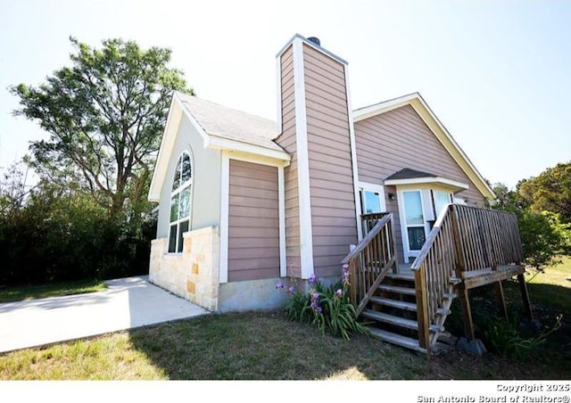view of front of house featuring a wooden deck, a chimney, and stone siding