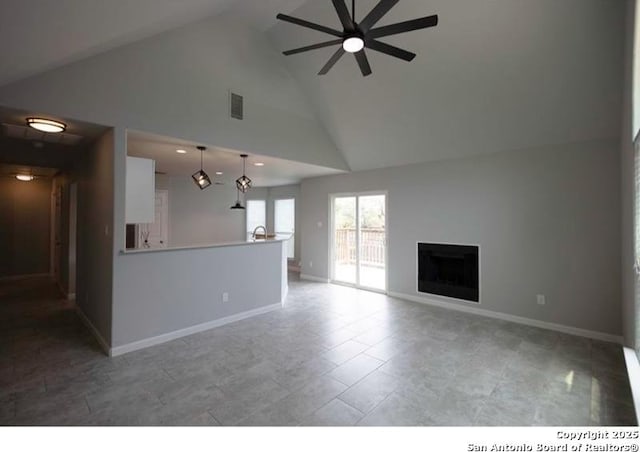 unfurnished living room with baseboards, a ceiling fan, a fireplace, and high vaulted ceiling