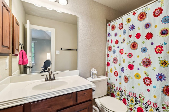 bathroom featuring toilet, a textured wall, a shower with curtain, and vanity