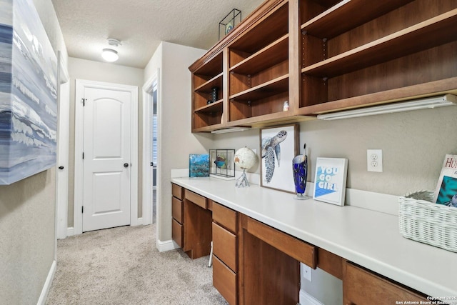 home office featuring light colored carpet, a textured ceiling, and baseboards