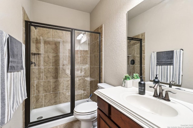 full bath featuring vanity, toilet, a textured wall, and a stall shower