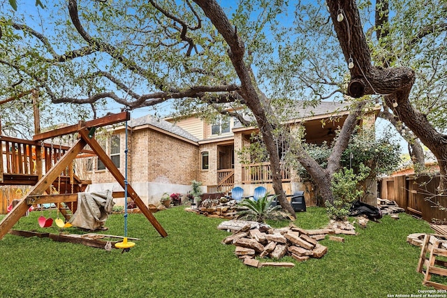 rear view of house featuring a fenced backyard, a ceiling fan, a yard, and brick siding