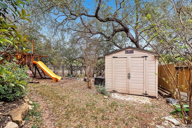 view of shed with fence and a playground