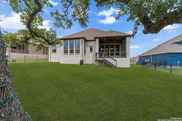 rear view of property featuring stairs, a fenced backyard, a yard, and brick siding