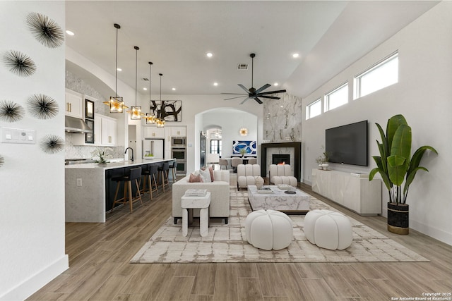 living room featuring arched walkways, ceiling fan with notable chandelier, recessed lighting, a towering ceiling, and visible vents