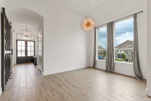 unfurnished dining area featuring baseboards, light wood finished floors, and a notable chandelier