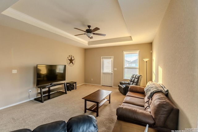 living room featuring a raised ceiling, ceiling fan, baseboards, and carpet floors