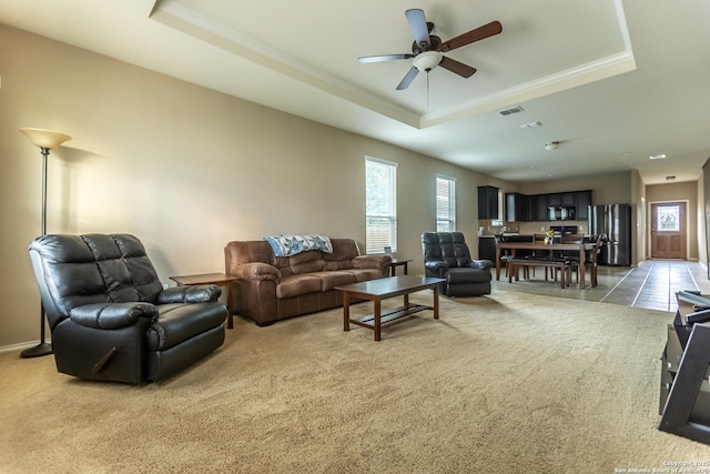 living room featuring ceiling fan, light carpet, and a tray ceiling