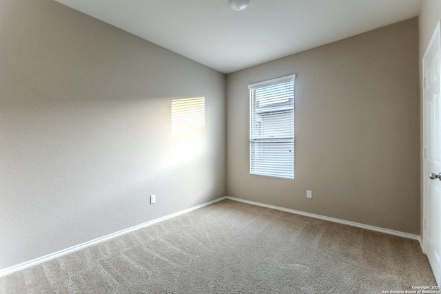 carpeted empty room with baseboards and vaulted ceiling