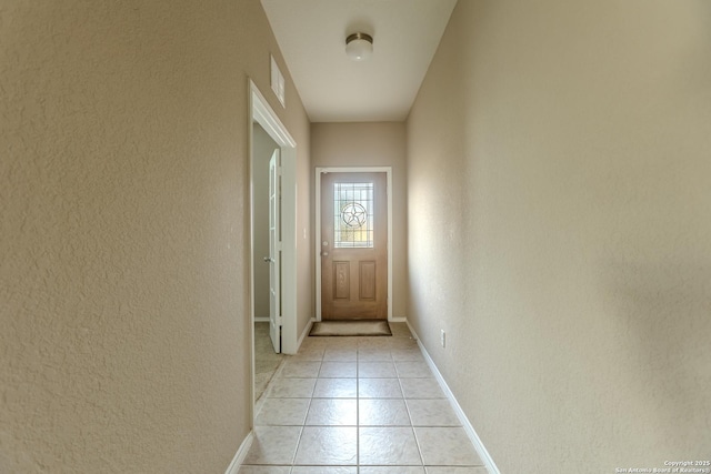 entryway featuring baseboards, a textured wall, light tile patterned flooring, and visible vents