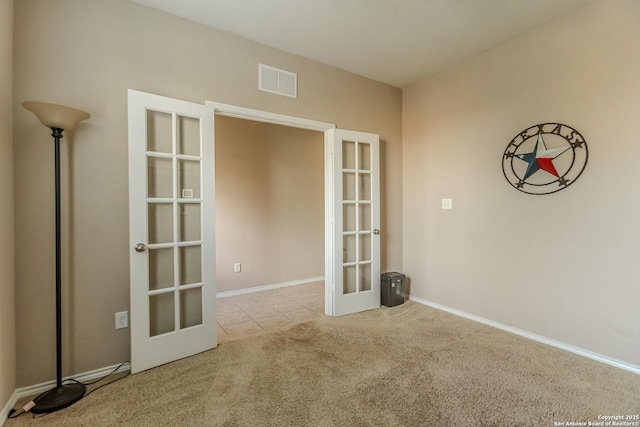 tiled spare room with french doors, carpet flooring, baseboards, and visible vents